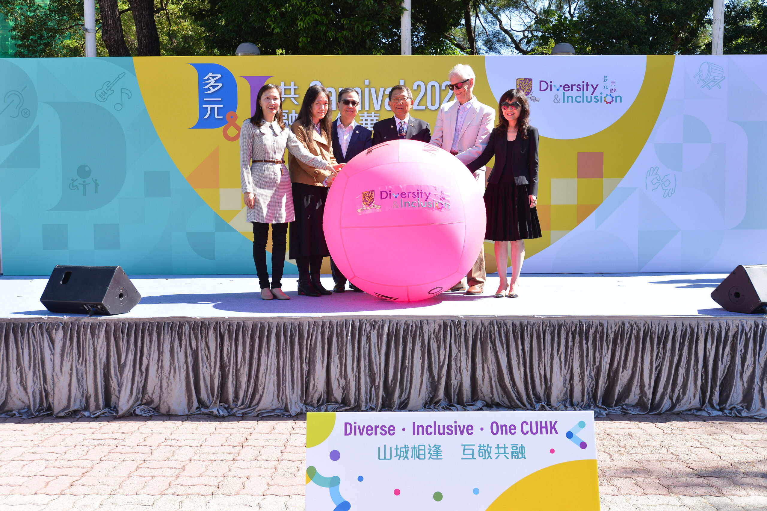 The guests stand on a stage with a large pink kin-ball displaying "Diversity & Inclusion."