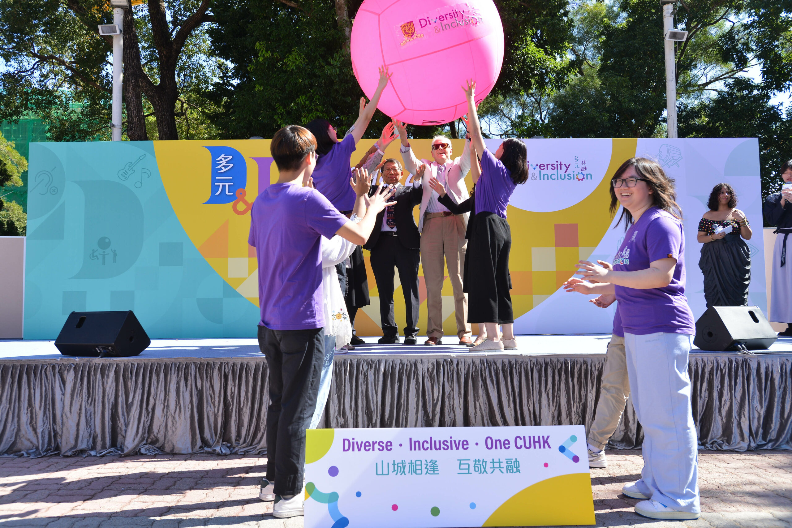 The guests and student ambassadors stands on a stage with a large pink kin-ball displaying "Diversity & Inclusion."