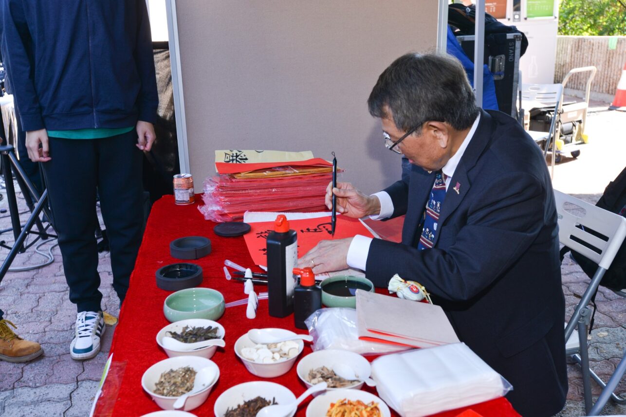 Prof. Rocky Tuan writes fai chun at the booth managed by the Mainland Undergraduate Association at D&I Carnival 2024.