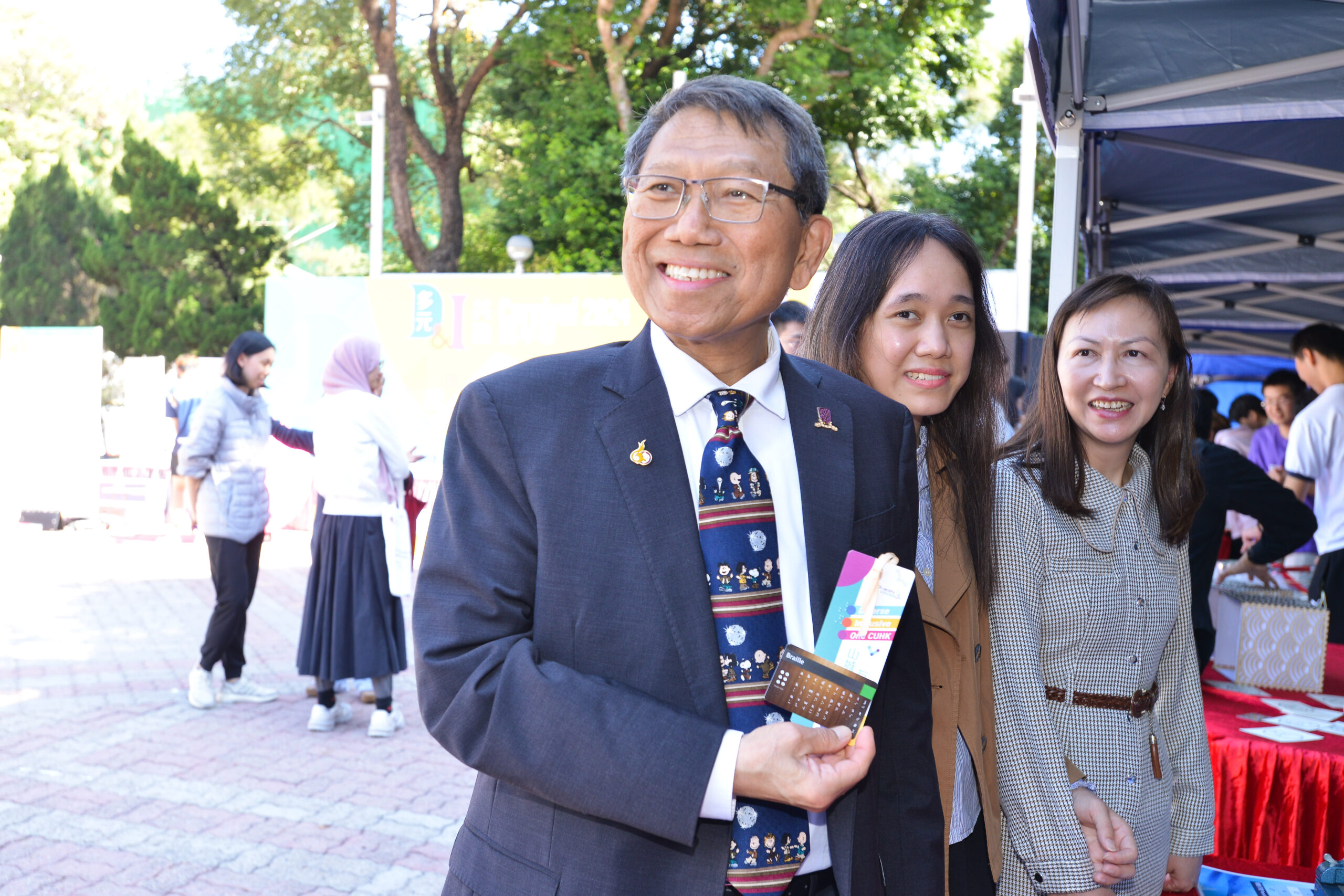 Prof. Rocky Tuan is holding the braille bookmark he made during the workshop and smiling.