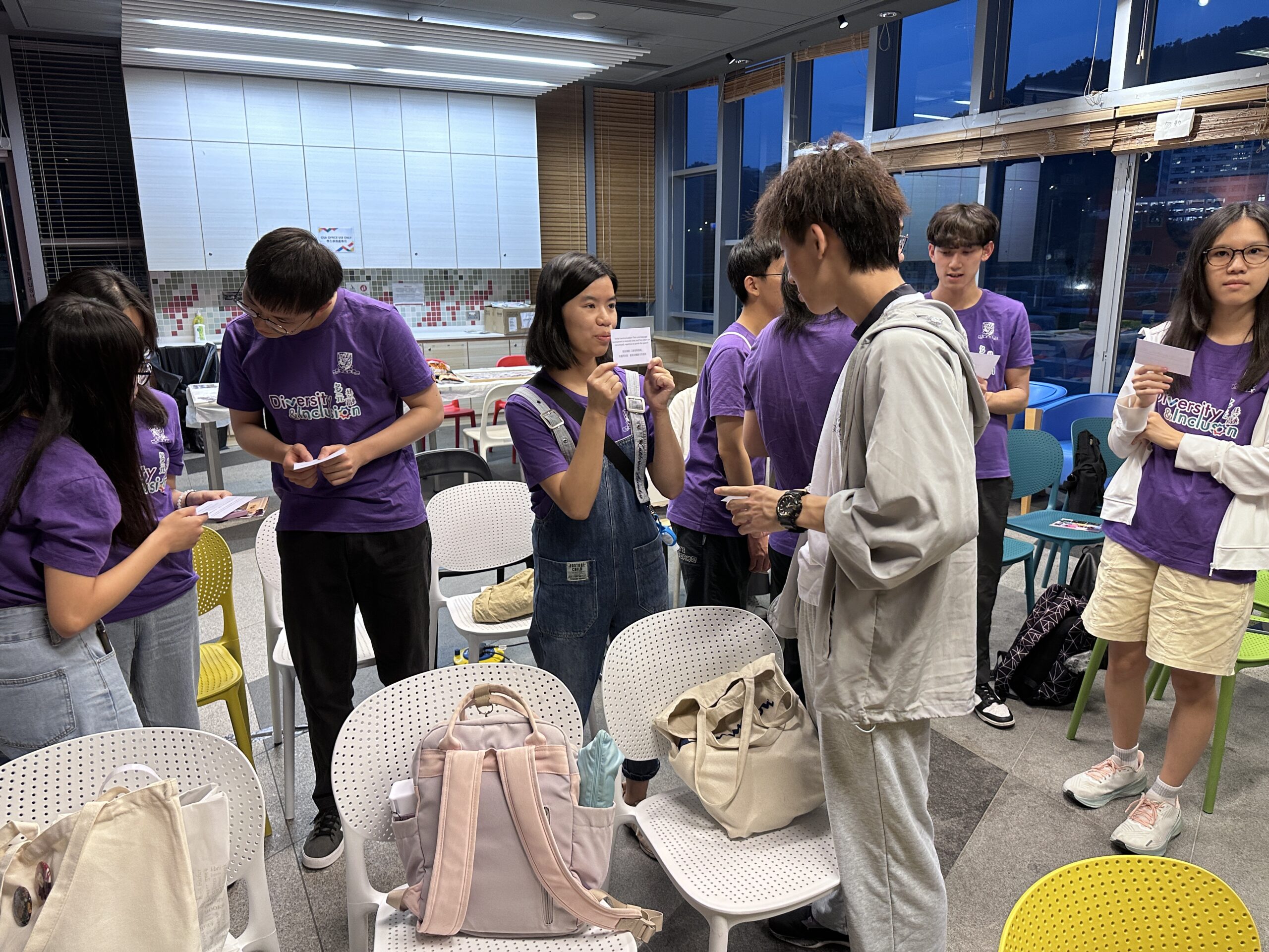 A group of ambassadors wearing purple "Diversity & Inclusion" shirts are engaged in an ice-breaking game at the D&I Ambassador Programme Closing Ceremony.