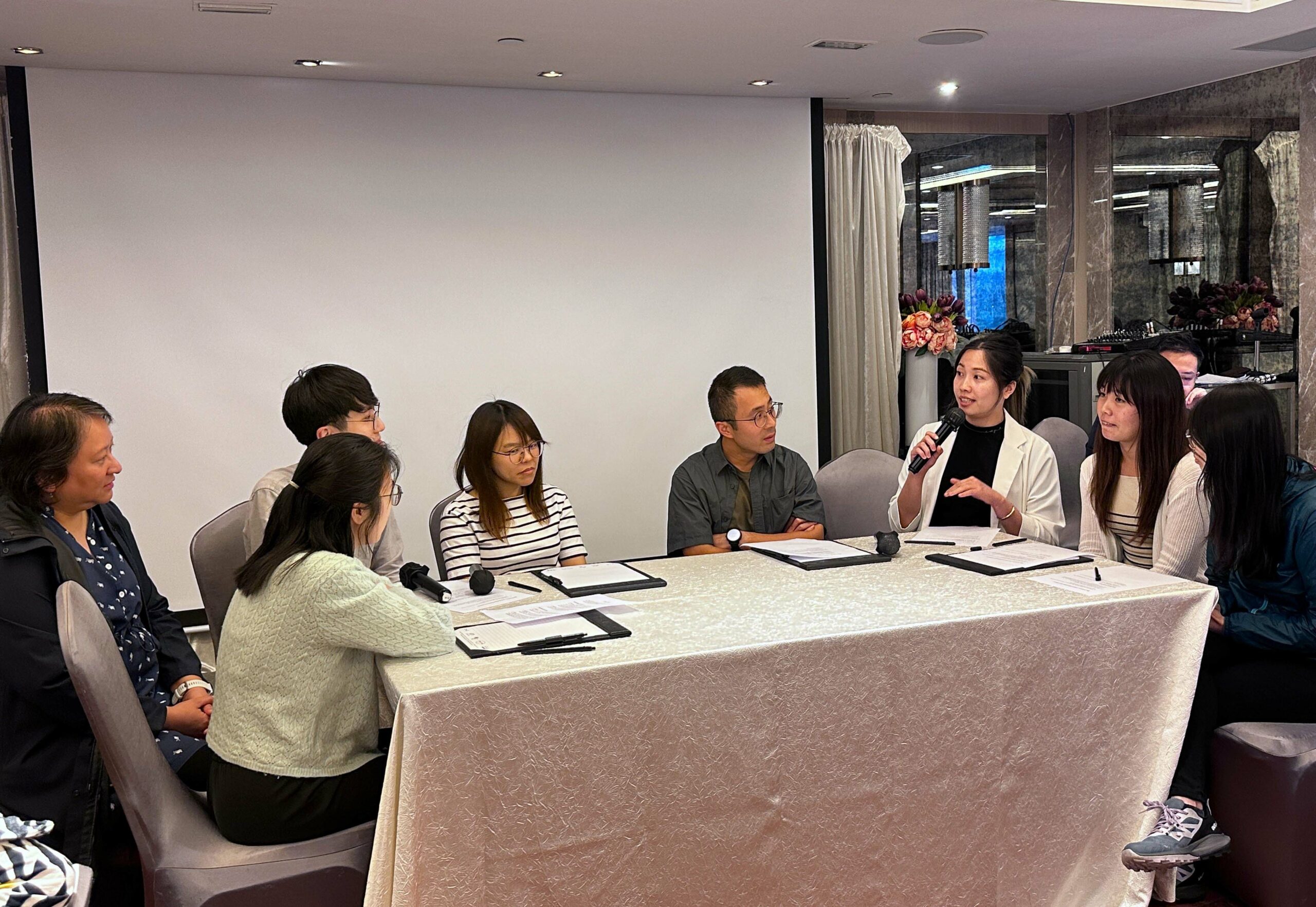 Seven participants (Group C) sit around a table, each holding a microphone, engaged in a conciliation role play session.