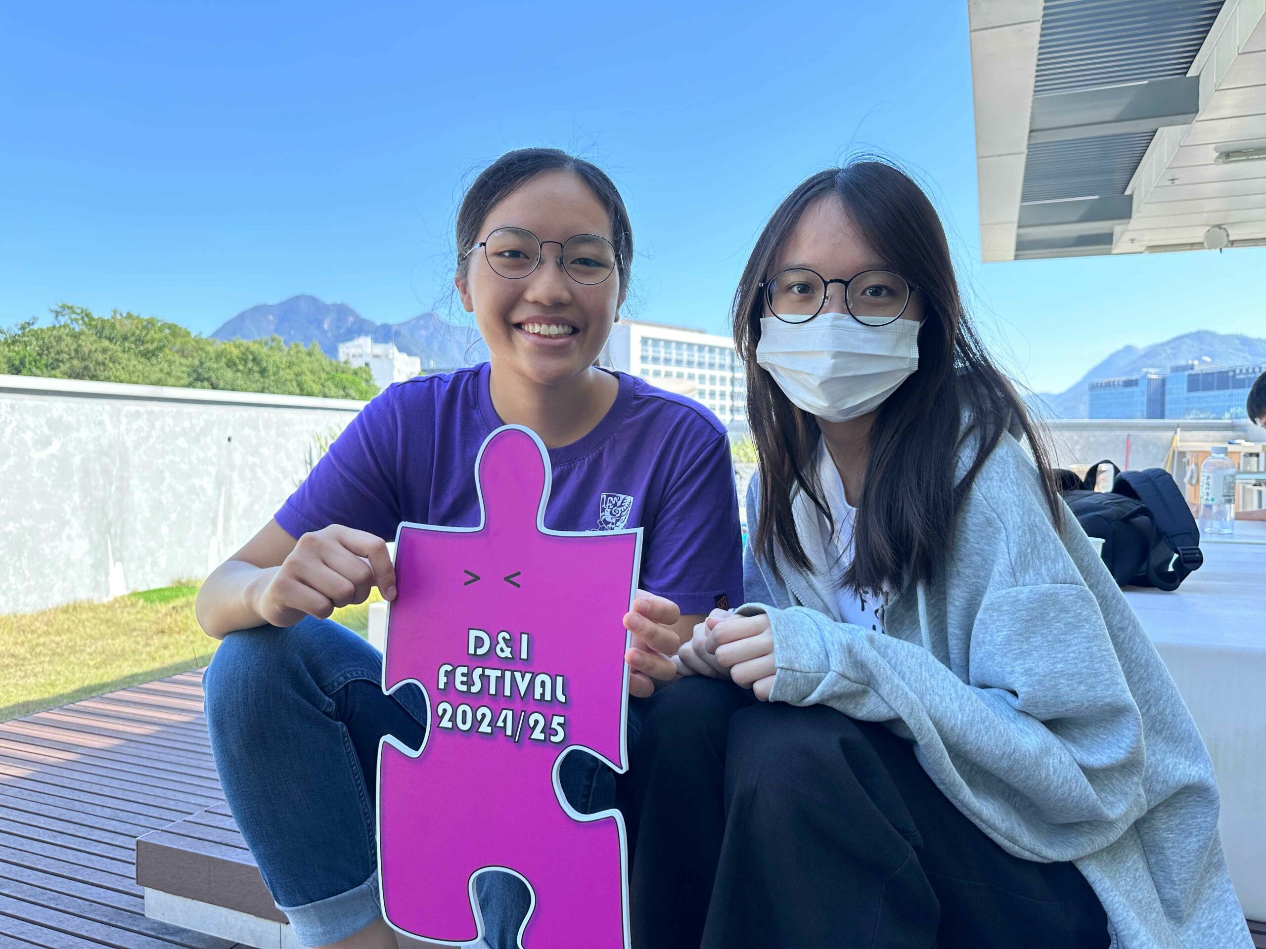 The D&I ambassador and a participant are holding colorful props promoting D&I festivals, smiling.